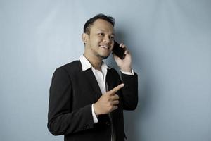 Portrait of an Asian businessman wearing a black suit smiling while talking on the phone photo