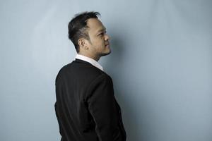 A portrait of a happy attractive Asian man is smiling wearing suit isolated by a blue background photo