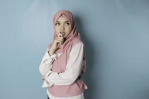 Portrait of a thoughtful young Muslim woman wearing pink hijab looking aside photo