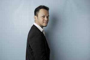 A portrait of a happy attractive Asian man is smiling wearing suit isolated by a blue background photo