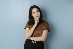 Portrait of a thoughtful young casual girl wearing a brown shirt looking aside isolated over blue background photo