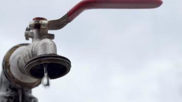 Wasserhahn auf dem Hintergrund der Natur. Das Öffnen oder Schließen eines Wasserhahns, um Wasser zu sparen, weist auf ein Problem mit Wassermangel hin. Rustikaler Brunnen mit Tageslicht. selektiver Fokus mit unscharfem Hintergrund. video