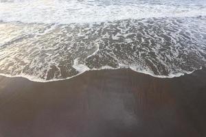 suave ola de océano azul en la playa de arena. antecedentes. foto