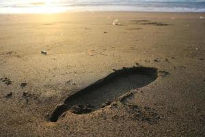 Human footprint on sand summer tropical beach at sunrise background with copyspace. photo