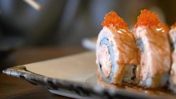 traditionelles japanisches essen. Nahansicht. Sushi-Koch dekoriert mit Sauce frisch zubereitete Sushi-Rollen, serviert auf einem schönen Teller. Kunstausgabe in einem Restaurant. langsam mit Stäbchen video