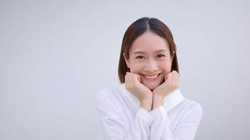 süßes asiatisches mädchen, das glücklich lächelt und ihr gesicht streichelt. zeigen positive Emotionen durch we video