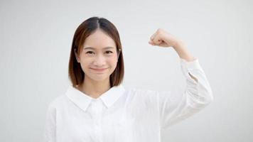 Cheerful Asian girl raising her arms and showing off her muscles looks confident video