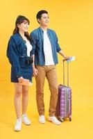feliz emocionado joven pareja asiática turistas en colorido fondo amarillo foto