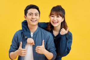 Attractive smiling young Asian couple being happy and amazed isolated on yellow studio background photo
