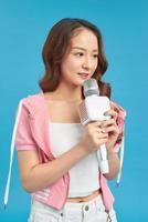 beautiful young woman singing karaoke isolated on blue photo