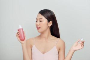 hermosa mujer aplicando tratamiento de agua en aerosol en la cara foto