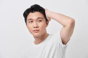 Confident smiling handsome young man in white t shirt. standing on the pure background, fixing his perfect hairstyle photo