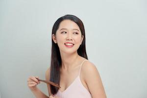 Portrait of cute young woman on white background combing hair. photo