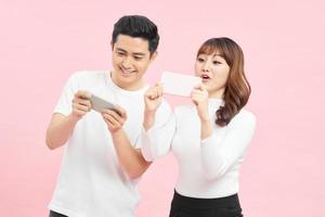 Laughing young couple friends guy girl in white t-shirts posing isolated on pink  background. photo