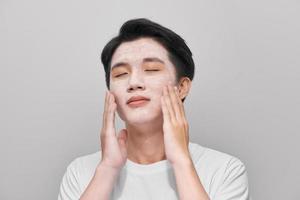 Handsome man with clay mask on his face against color background photo