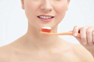 Young beautiful woman washing her perfect teeth, isolated on white background photo