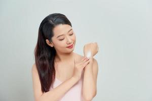 Portrait of happy smiling beautiful young woman touching skin or applying cream, isolated over white background photo