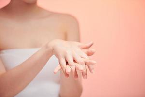 Beautiful young woman applying cosmetic moisturizer on hands photo