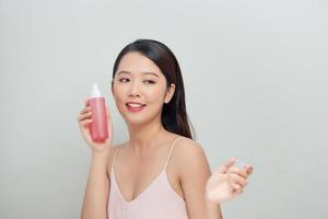 retrato de belleza de una atractiva joven asiática de pie, mostrando una botella foto