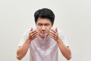 Handsome man is washing up, splash of water, on a white background photo