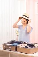 mujeres jóvenes eligiendo sombrero con ropa y maleta. preparándonos para las vacaciones de verano foto