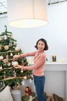 Smiling young woman is preparing Christmas decoration in her home. photo