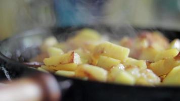 asar papas frescas en una sartén de hierro fundido con aceite de girasol. una vista de una estufa con una sartén llena de papas fritas doradas en una cocina real. comida cocinada en una sartén casera. video