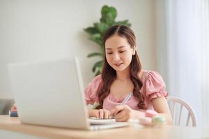 mujer joven atractiva que trabaja con computadora portátil y documentos mientras está sentada en casa, apartamento foto