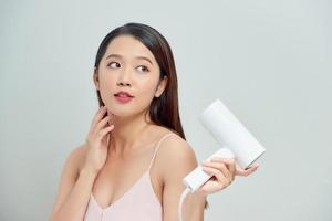 Happy young woman blow drying hair photo