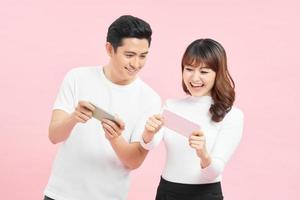 Young couple with mobile phones on color background photo