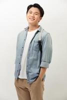 Handsome asian man with backpack smiling standing against white wall photo