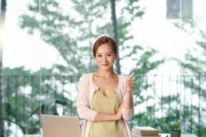 beautiful recruiter showing thumb up while standing near coworkers in office photo