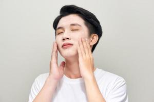 Handsome man with clay mask on his face against white background photo