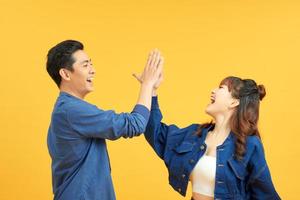 Joyful man and woman greeting each other with high five on yellow background photo
