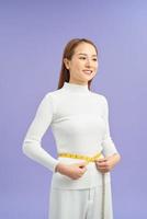 Portrait of a happy young asian woman holding measuring tape around her waist photo