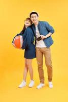 Young smiling happy couple tourists in casual summer attire with beach accessories on colorful yellow studio background photo