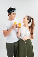 feliz pareja joven con vasos de jugo de naranja aislado sobre un fondo blanco. foto