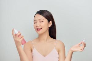 Beautiful woman applying spray water treatment on face photo