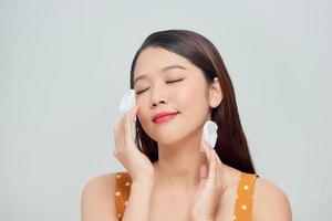 Photo of asian woman holds cotton pads near face isolated on white background