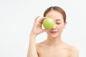 Young healthy woman holding green apple over her eyes on white background photo