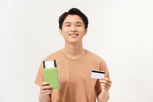 retrato de un joven feliz con pasaporte con boletos y mostrando una tarjeta de crédito de plástico aislada foto