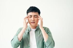 healthcare, pain, stress, age and people concept - Young asian man suffering from headache on white background photo