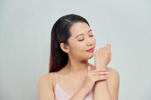 Smiling young woman applies cream on her hands photo