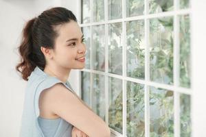 Lovable lady standing near window and looking at beautiful garden. photo