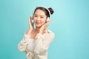 Teenage girl wearing headphones making gesture against blue background. photo