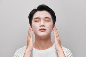Handsome man with clay mask on his face against white background photo