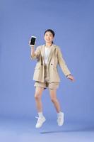 Cheerful girl jumping up and newest smartphone showing empty screen, enjoying new application for mobile phone photo