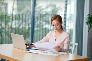 atractiva mujer asiática usando una laptop en casa foto