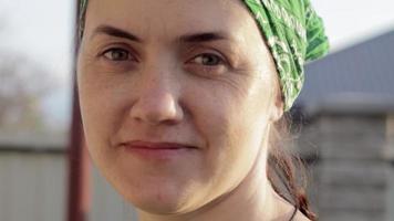 avvicinamento ritratto di un' caucasico donna guardare a il telecamera e sorridente. bellissimo giovane donna senza trucco nel un' verde sole cappello su un' soleggiato estate giorno all'aperto. raggio di sole. video