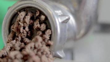 An incognito woman cooks meat in a home kitchen. Minced meat on a manual mechanical meat grinder. Fresh boiled meat is ground on an old metal meat grinder, close-up in the kitchen. video